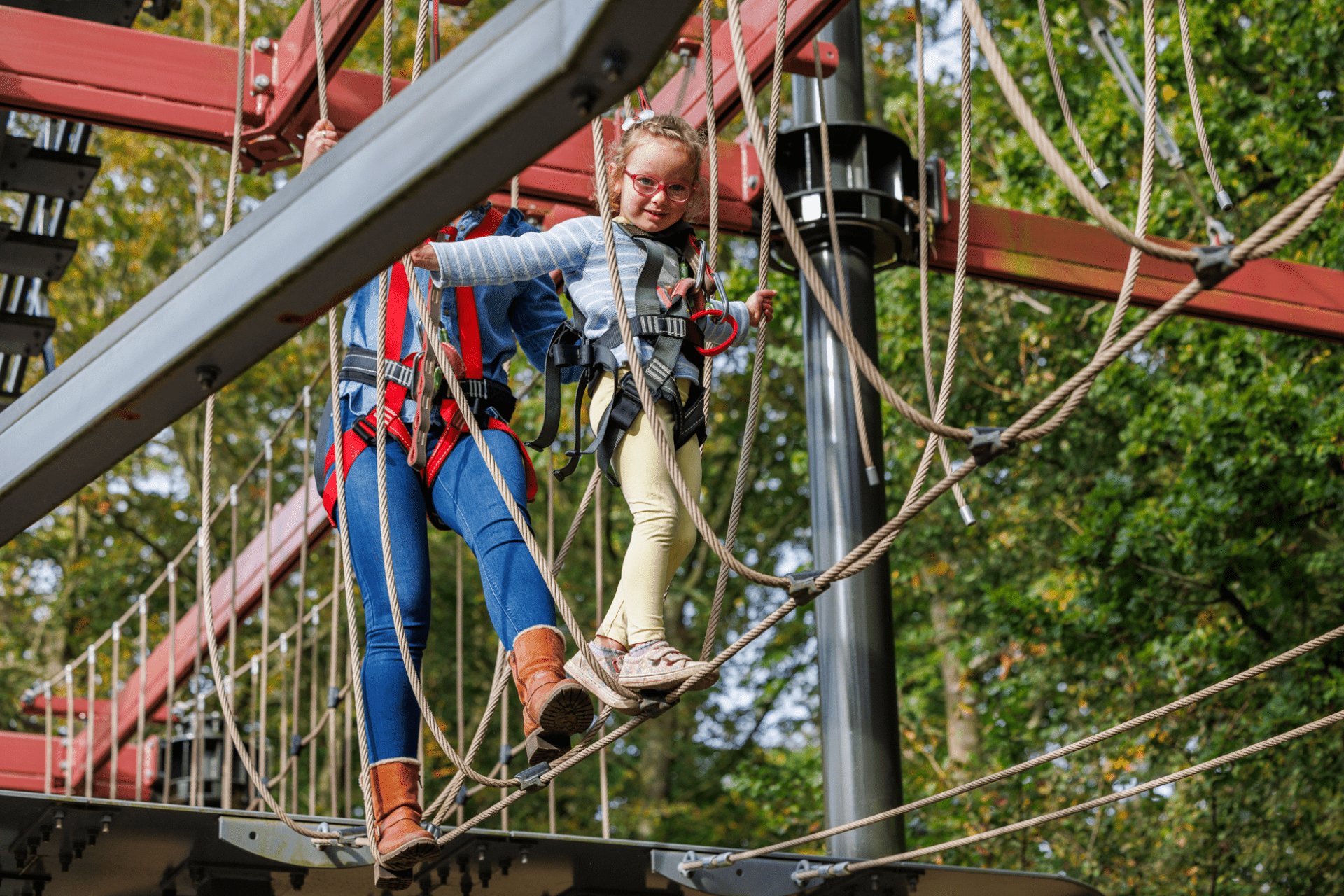 Visitor taking on the high ropes course at ROARR! Dinosaur Adventure, navigating elevated obstacles while secured with a safety harness.