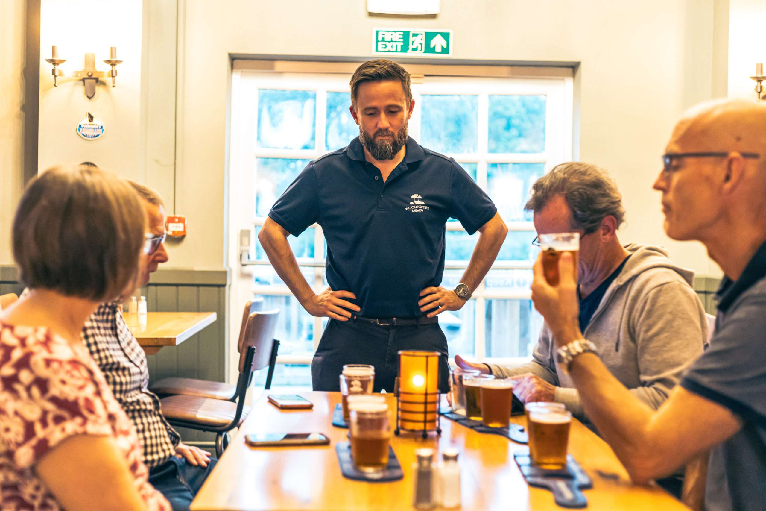 Woodforde’s Brewery tour guide leading a beer tasting session with visitors in the brewery’s tasting room.Provide your feedback on BizChat