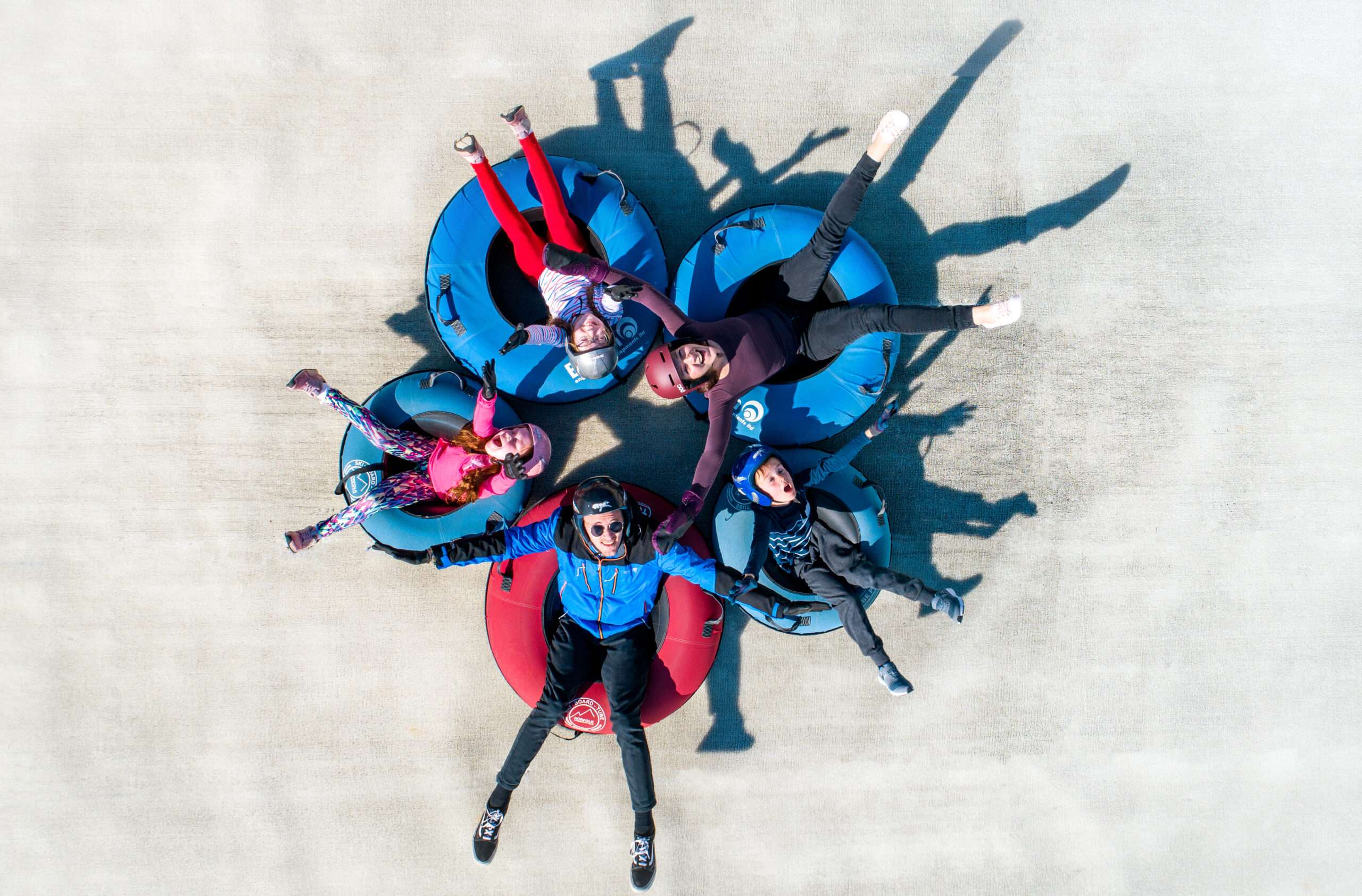 Overhead view of participants seated in a circle on snow tubes, creating a star-shaped formation on the tubing slope.
