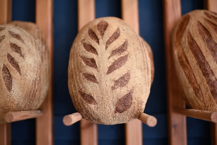 Decoratively scored artisan sourdough loaf standing upright on display at Bread Source bakery.