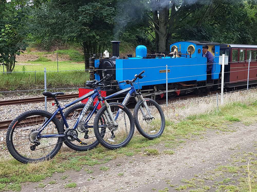Bicycles parked alongside the Bure Valley Railway steam train, highlighting the popular cycle and rail experience between Aylsham and Wroxham.