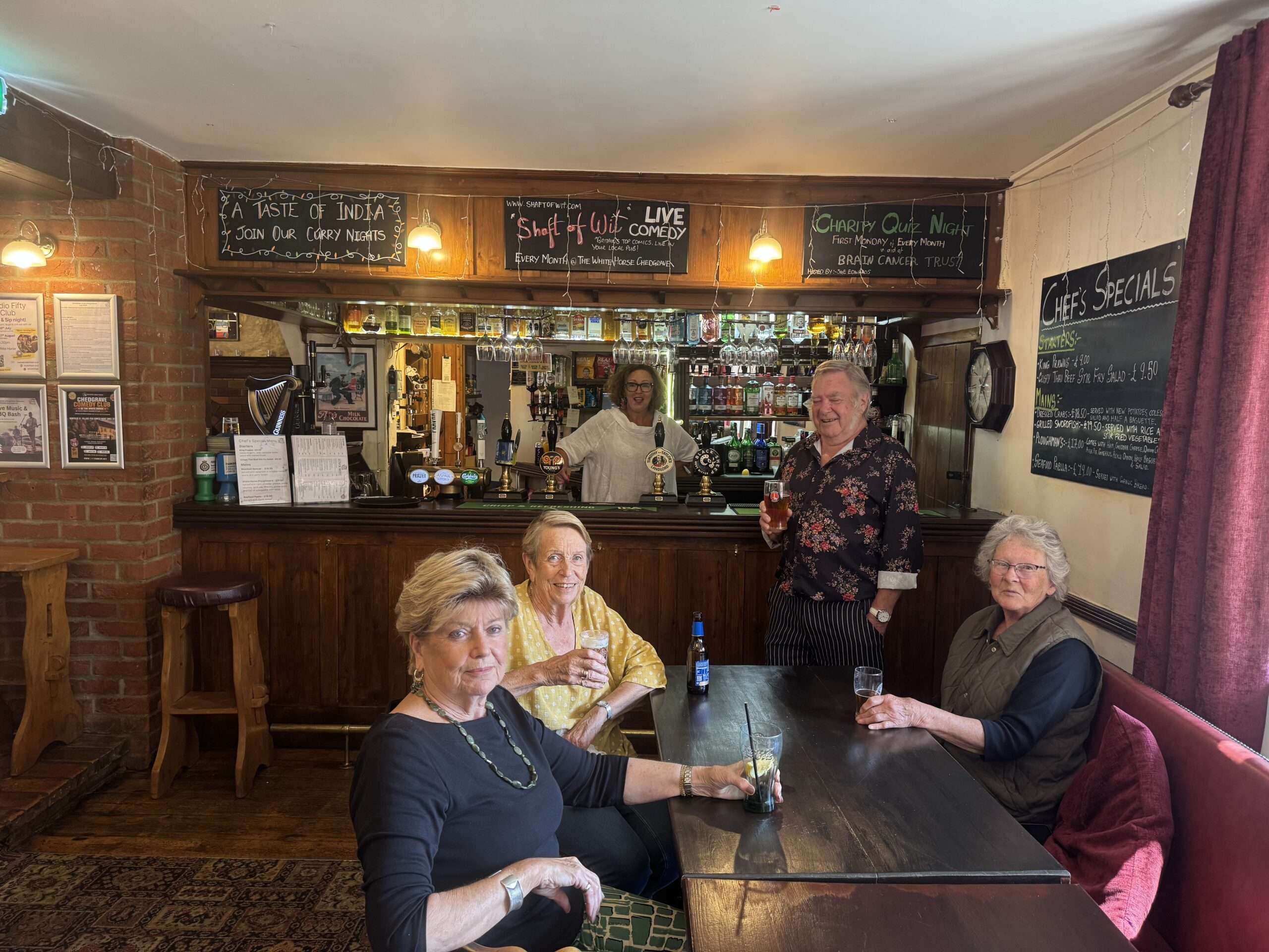 Customers enjoying drinks and conversation inside The White Horse pub, showing the traditional bar area
