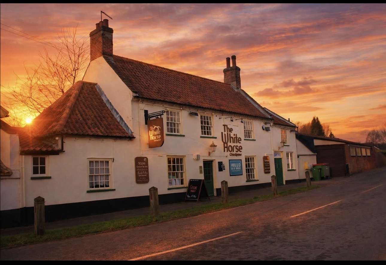 The White Horse pub in Loddon at sunset, featuring the historic building illuminated against a colourful evening sky.