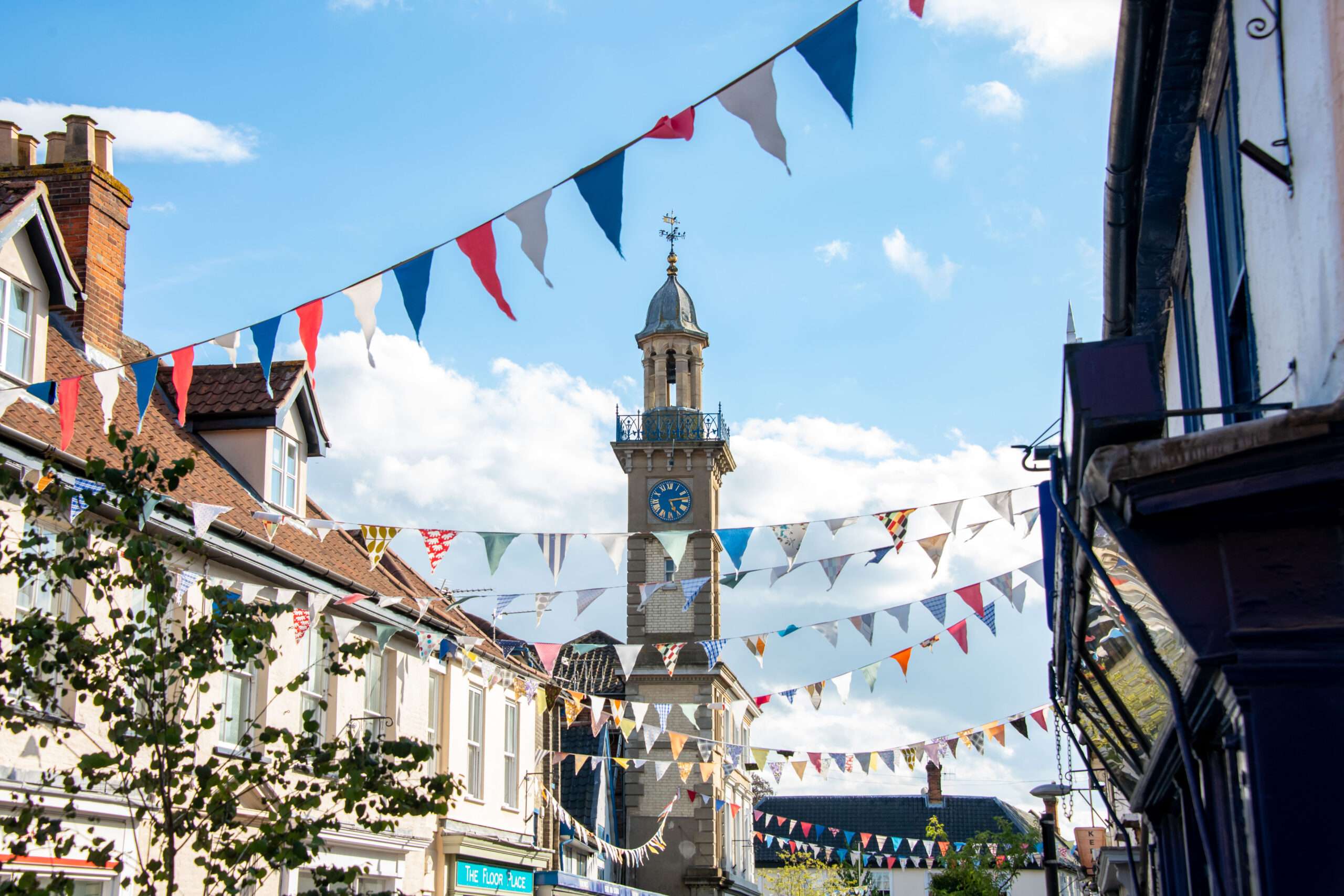 Harleston clock tower rising above historic buildings decorated with bunting