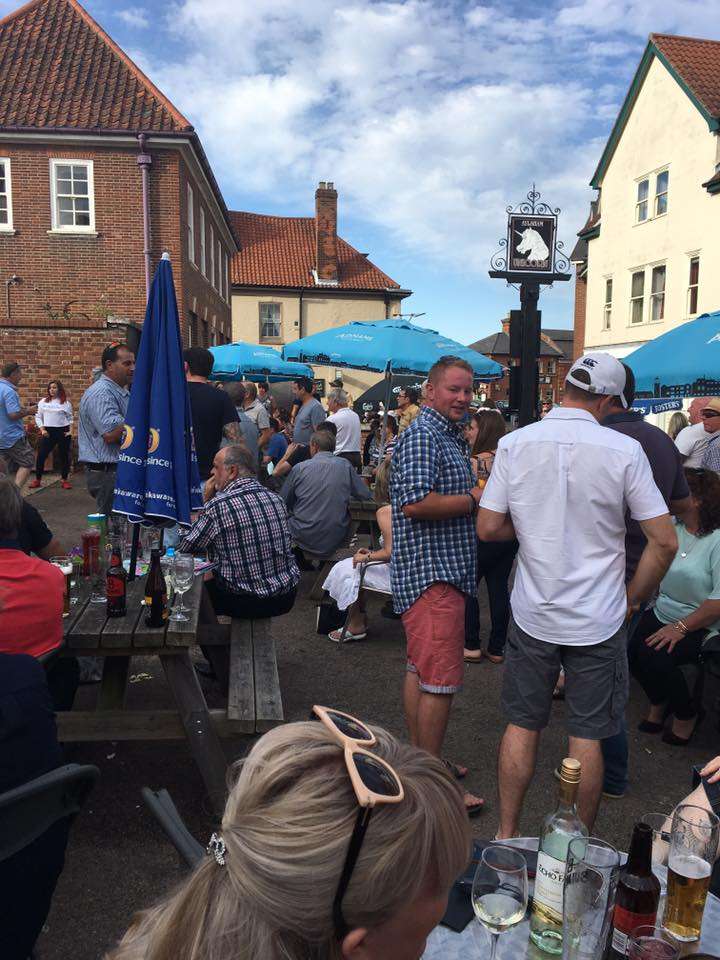 Visitors enjoying drinks and socialising outside The Unicorn in Aylsham during a lively outdoor event.