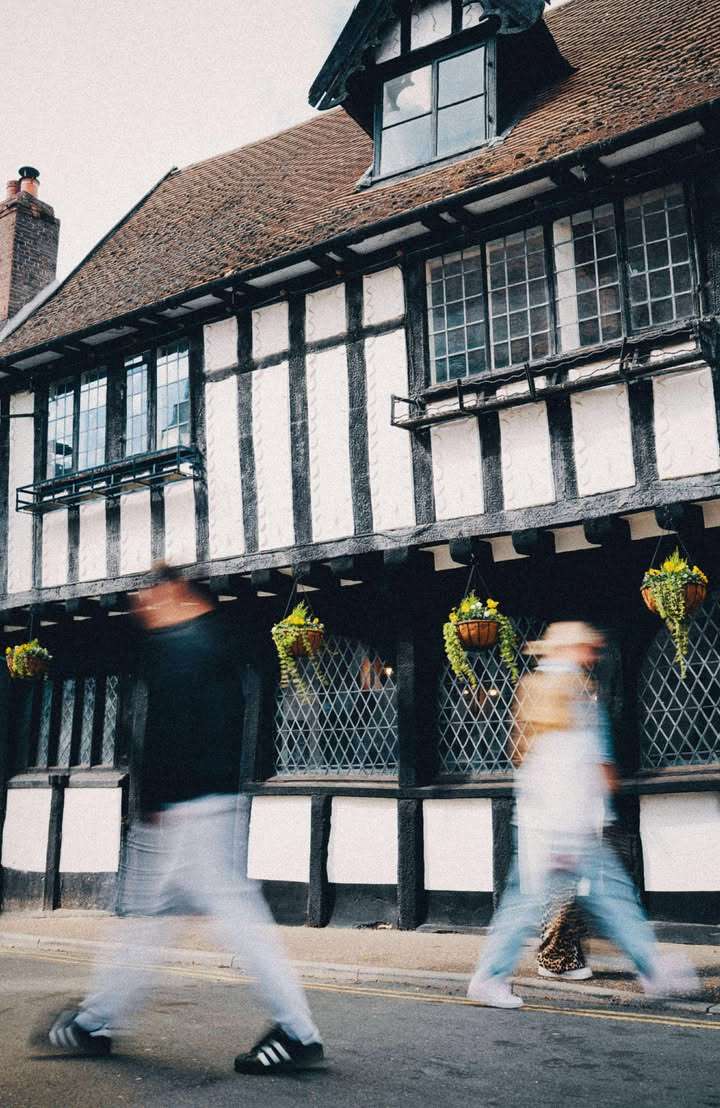 The Green Dragon's distinctive timber-framed exterior with leaded windows and flower baskets, showcasing the building's historic character in the heart of Wymondham.