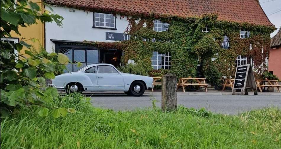 Traditional countryside building at the Cock Inn with ivy-clad walls, outdoor seating and parking area.