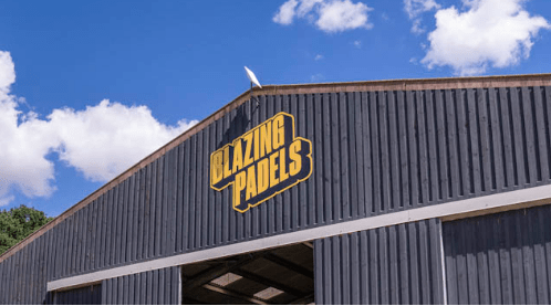 Blazing Padels sign displayed on the exterior of the padel venue at Salle Moor Farm, Norfolk, against a bright blue sky.