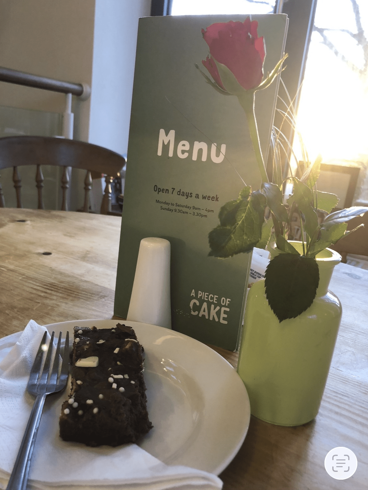 Café table and menu display inside A Piece of Cake in Coltishall, showcasing the welcoming interior.