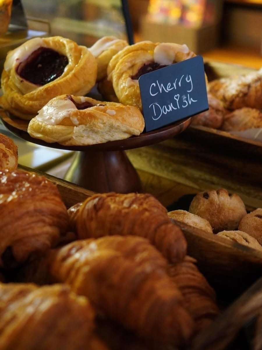 Freshly baked pastries including croissants, pain au chocolat and Danish pastries displayed on a café counter River Garden Pantry Thorpe St Andrew