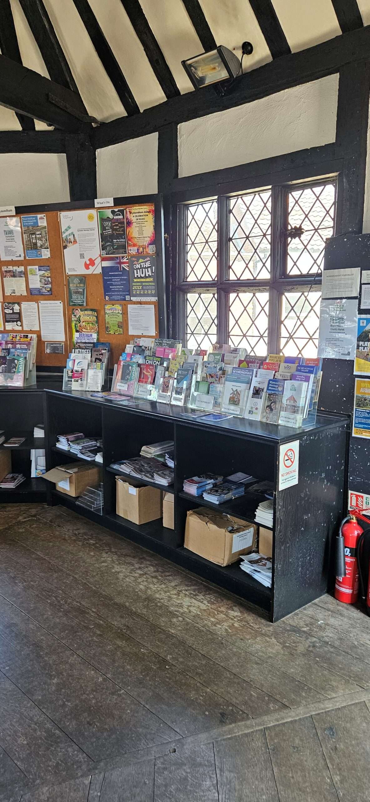 Tourist information displays and local leaflets arranged beneath leaded windows inside the historic Wymondham Tourist Information Centre.