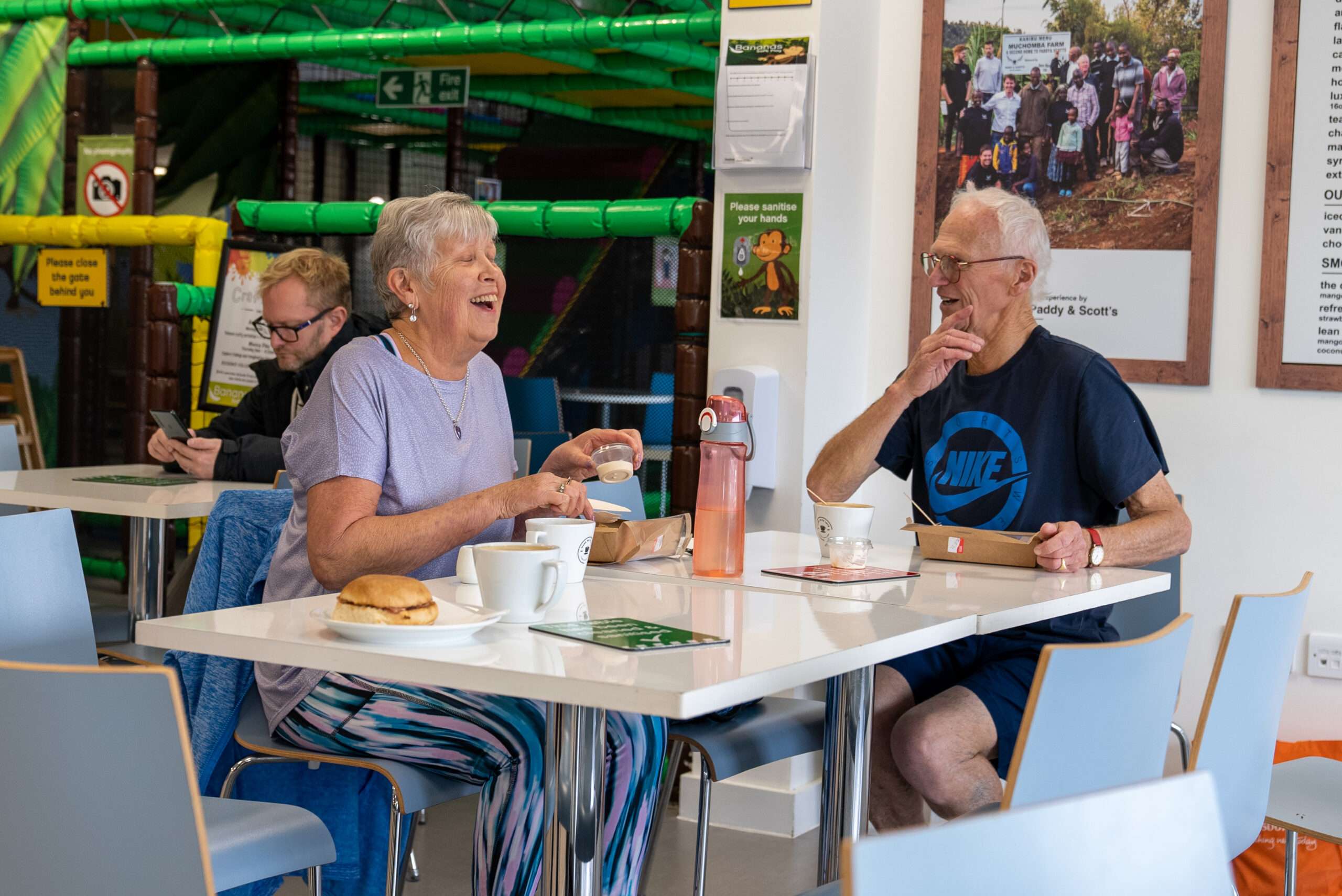 Visitors enjoying drinks and refreshments in the café seating area at Bananas Soft Play.