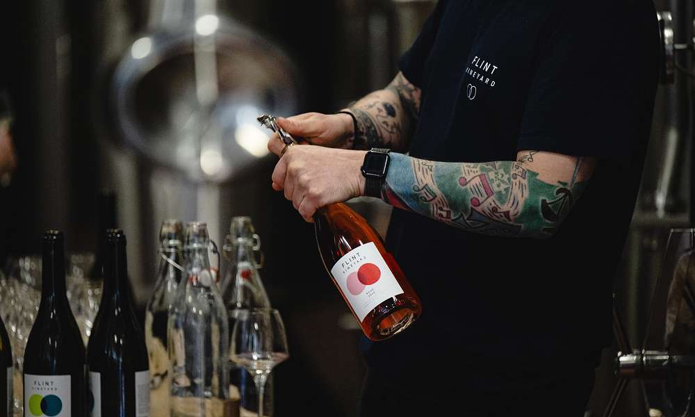Bottle of sparkling wine being prepared by hand in a winery, highlighting traditional production methods and craftsmanship.
